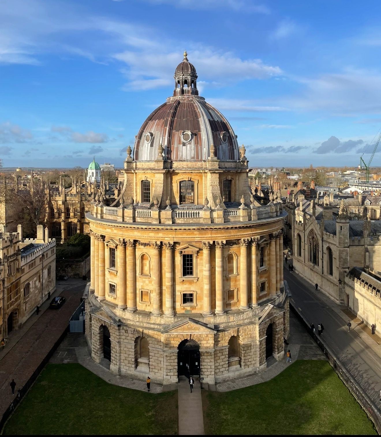 Aerial view of a historic domed building surrounded by medieval architecture under a clear blue sky.