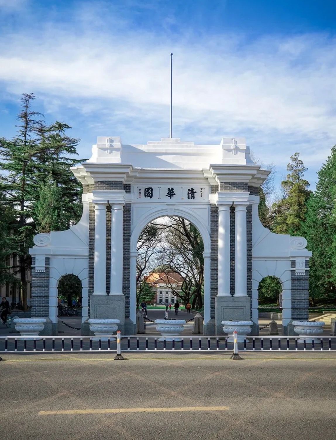 Historic stone archway with Chinese characters, surrounded by trees under a blue sky.